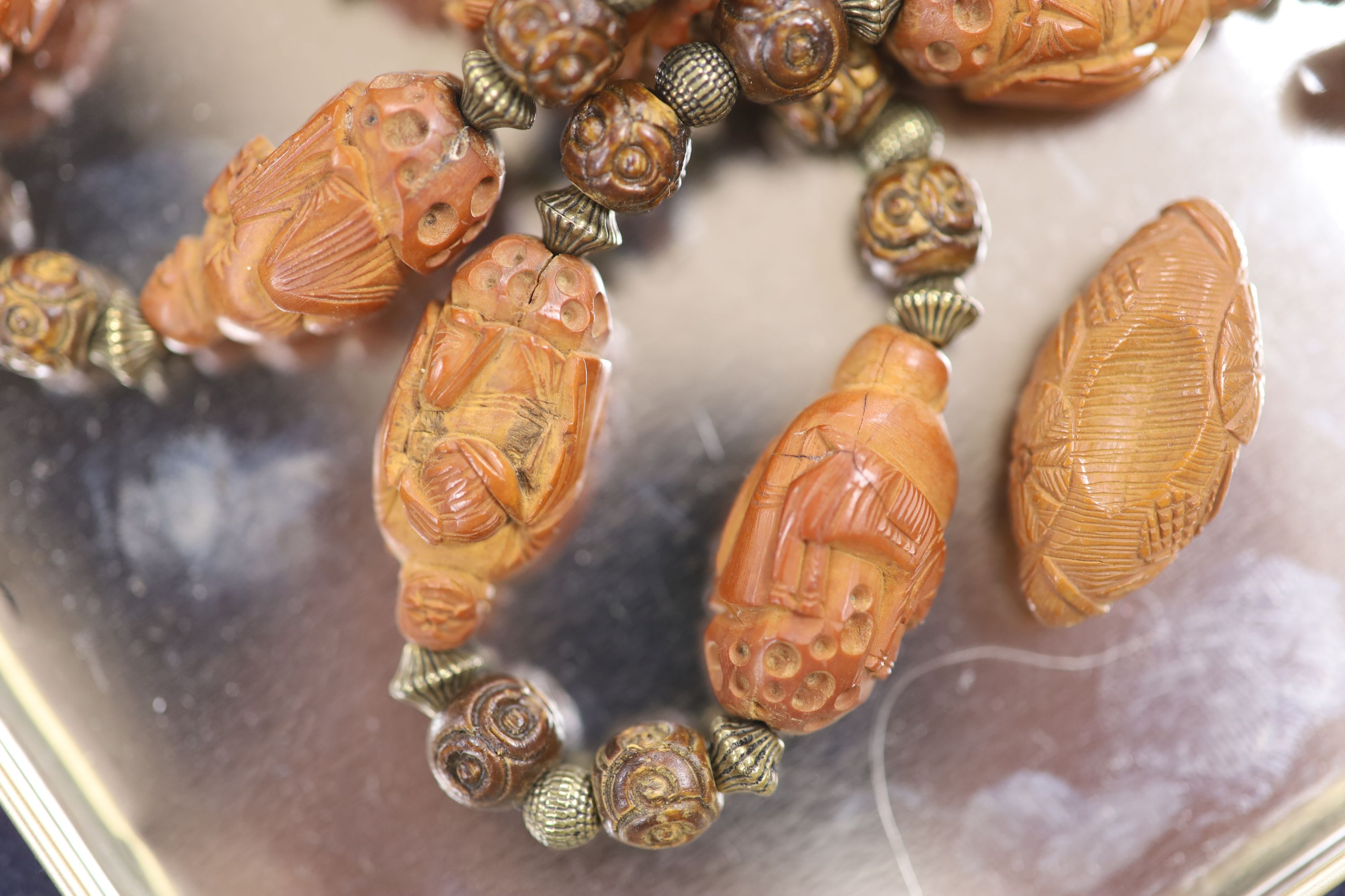 A Chinese peach stone or nut bead necklace, bracelet, a pair of earrings and two carved beads